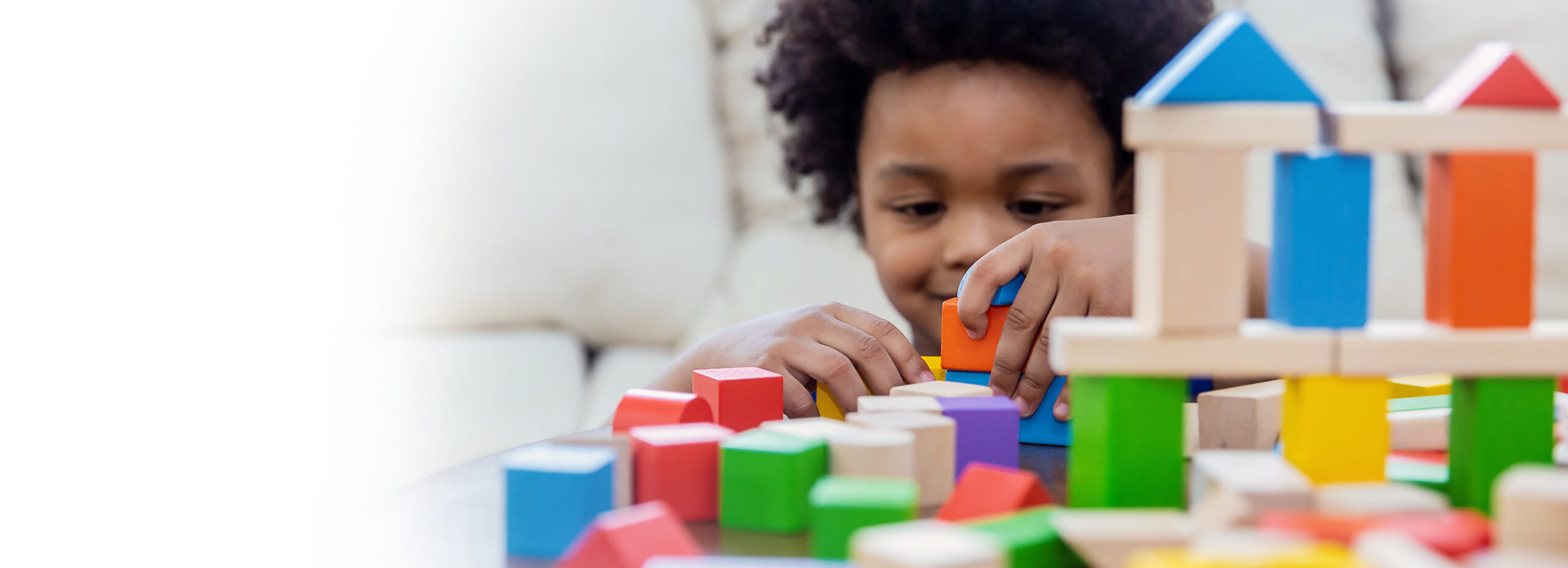 Child building a colourful block tower at Crayon College